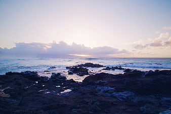 Dramatic Sunset Over Rocky Ocean Coastline with Clouds
