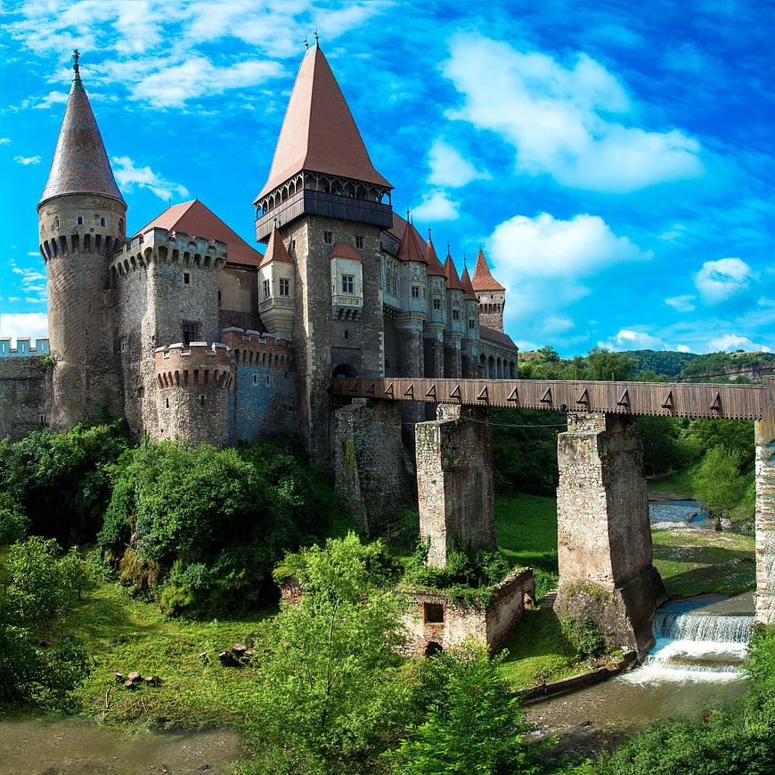 Bran Castle in Romania with Stone Bridge and Lush Green Landscape