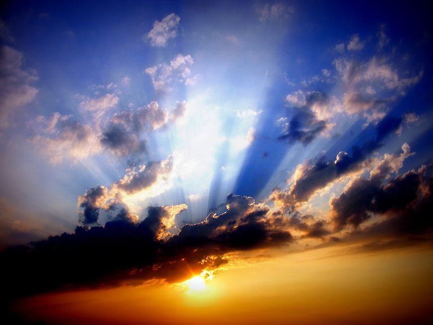 Dramatic sunset with sun rays breaking through clouds
