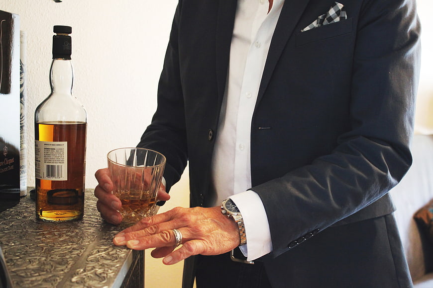 Man in Suit Holding Whiskey Glass at Bar