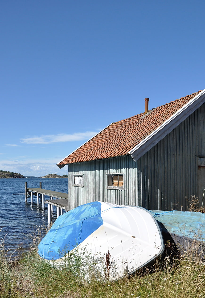 Rustic wooden boathouse with overturned boats by the sea