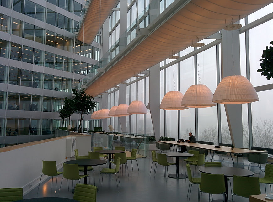 Modern office atrium with green chairs and large pendant lights