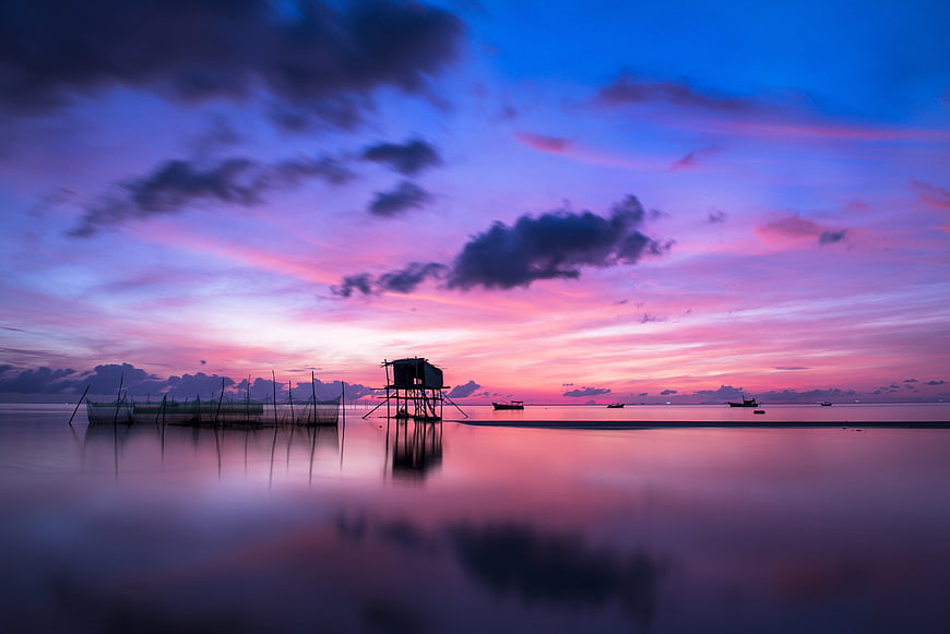 Serene Sunset Over Calm Sea with Fish Pens and Reflections