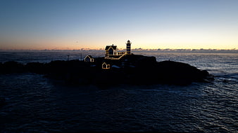 Lighthouse on Rocky Island at Dusk with Festive Lights