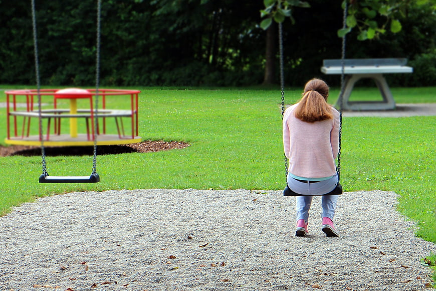 Woman sitting alone on a swing in a park