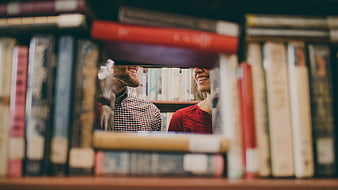 Happy couple smiling through gap in bookshelf