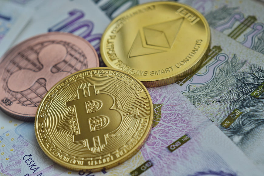 Bitcoin, Ethereum, and Ripple coins on Czech banknotes