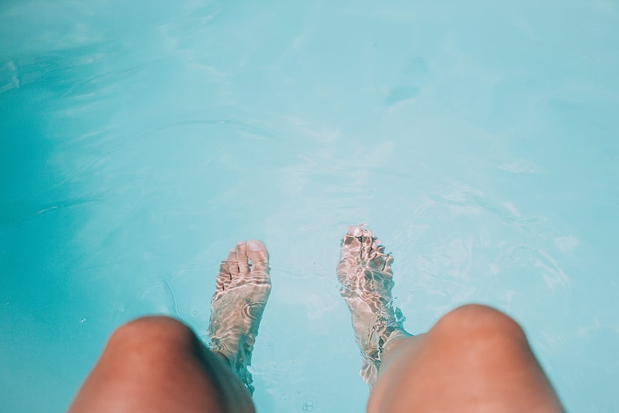 Relaxing feet in turquoise swimming pool water