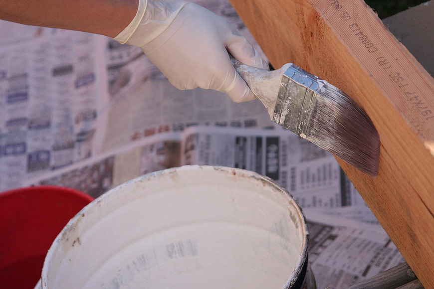 Hand in Glove Painting Wood with Brush and White Paint
