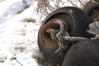 Rusty boat cleat with rope in snow