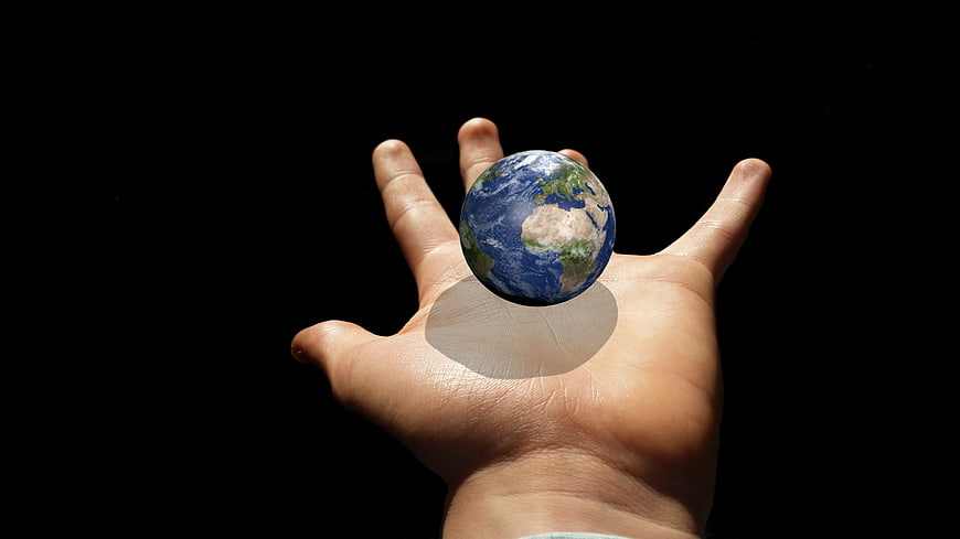Hand holding miniature Earth globe on black background