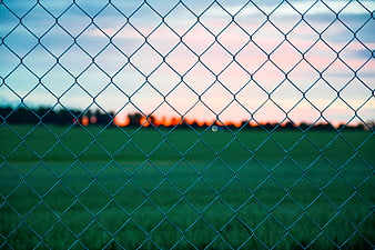 Chain link fence pattern against blurred sunset field background