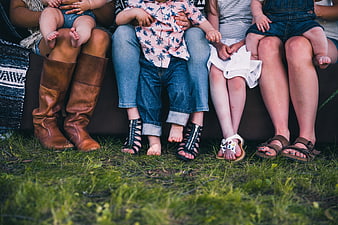 Close-up of family feet and footwear sitting on grass outdoors