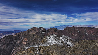 Panoramic View of Rugged Snow-Capped Mountain Peaks Under Blue Sky