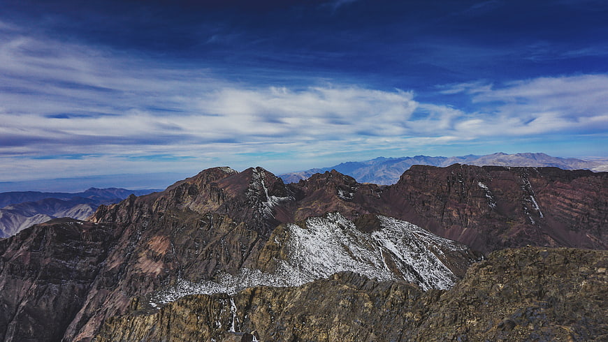 Panoramic View of Rugged Snow-Capped Mountain Peaks Under Blue Sky