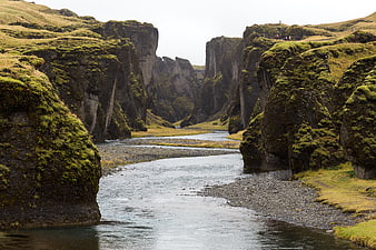 Moss-covered cliffs framing a river in a dramatic landscape