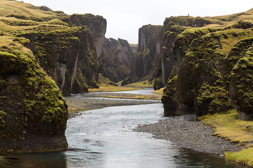 Moss-covered cliffs framing a river in a dramatic landscape