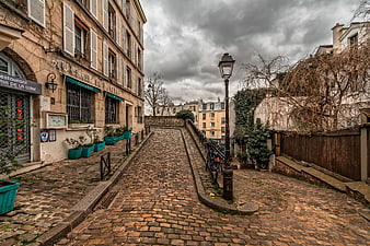 Cobblestone Street in Montmartre Paris Under Cloudy Sky