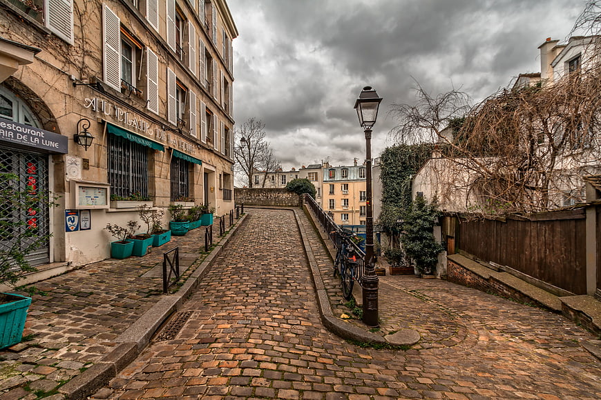Cobblestone Street in Montmartre Paris Under Cloudy Sky