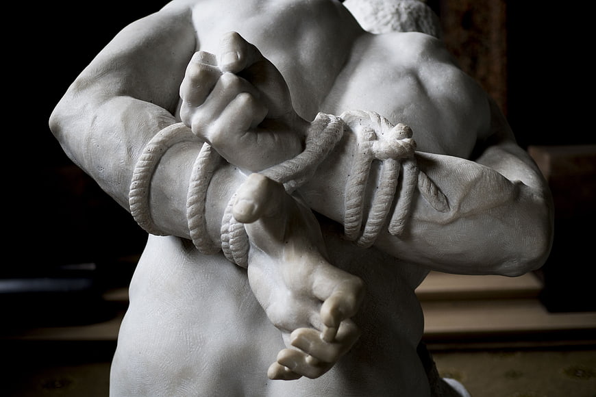 Close-up of marble sculpture with bound hands and rope