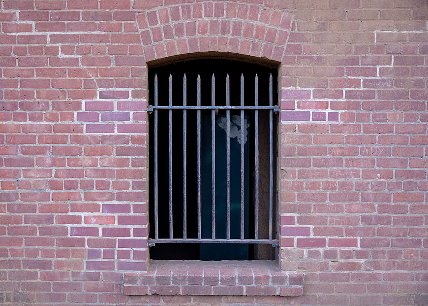 Weathered Brick Wall with Arched Barred Window