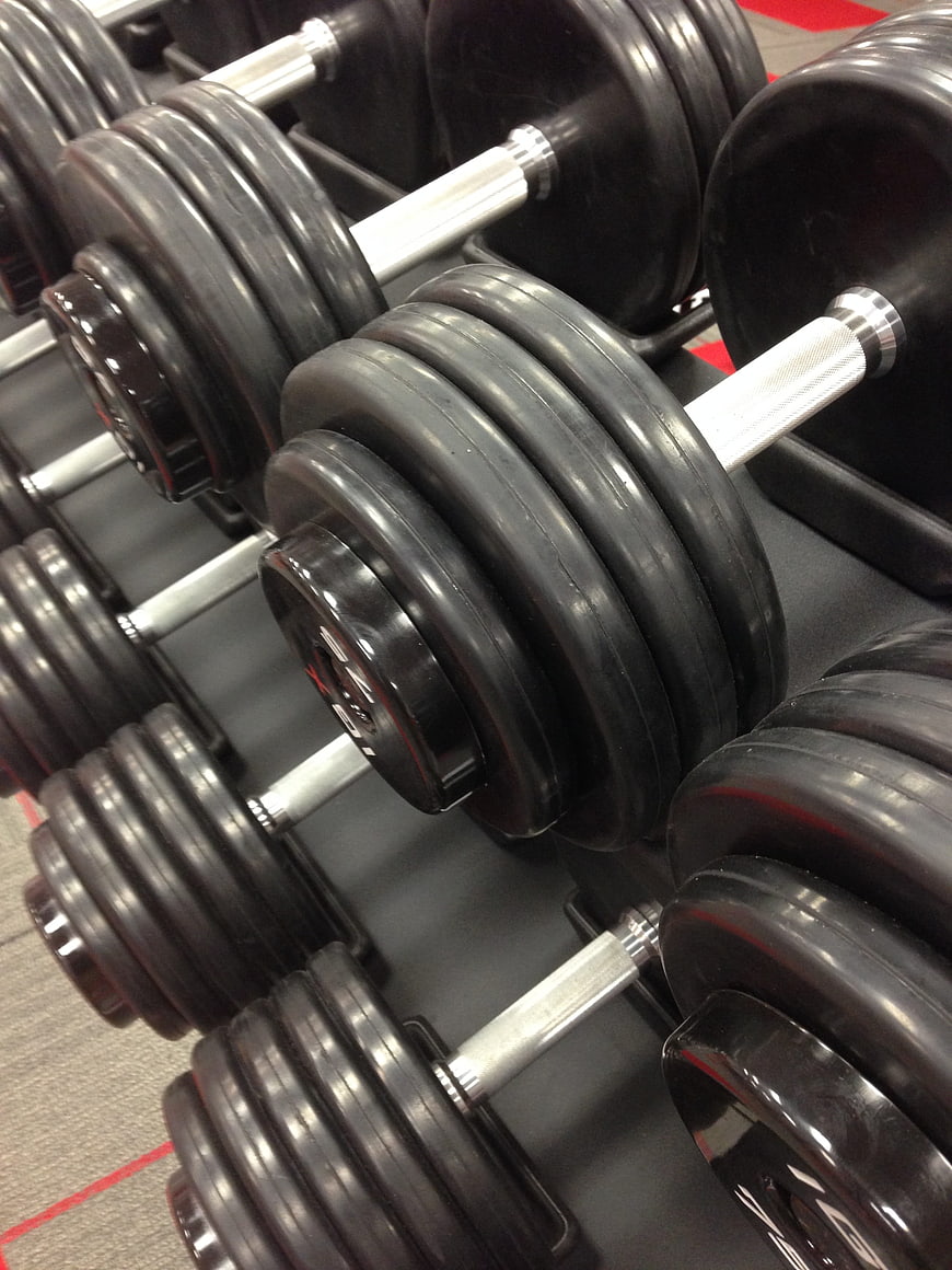 Close-up of black rubber dumbbells on a gym rack