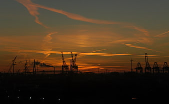 Silhouette of Port Cranes Against Dramatic Orange Sunset Sky