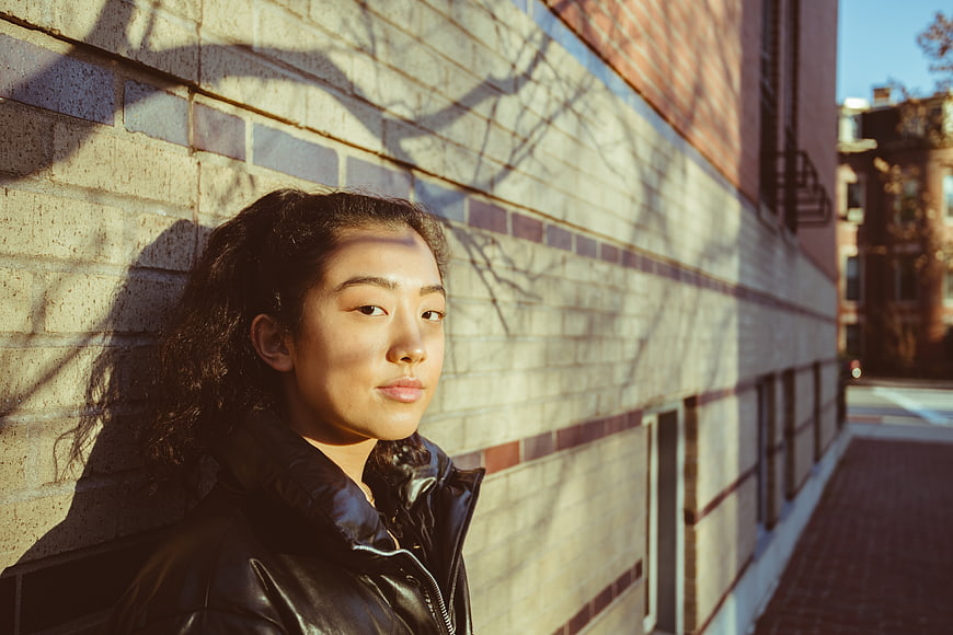 Asian Woman Portrait Against Brick Wall in Sunlight