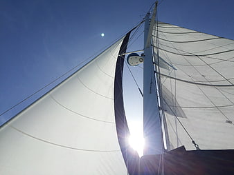 Sailboat Mast and Sails Backlit by Sun Against Blue Sky