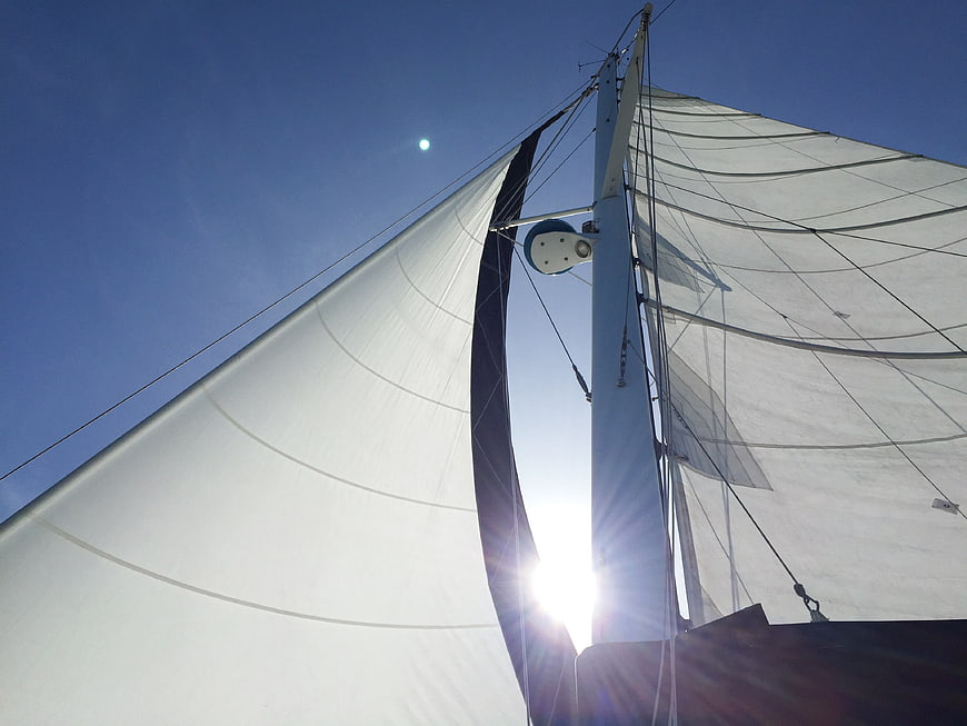 Sailboat Mast and Sails Backlit by Sun Against Blue Sky