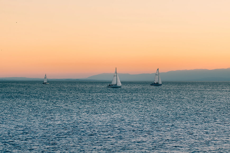 Three Sailboats on Calm Sea at Sunset