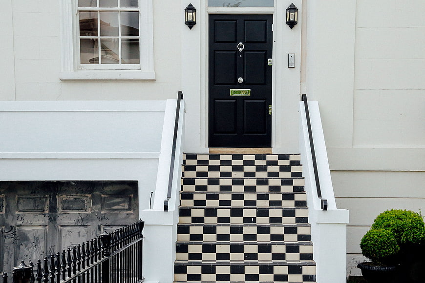 Classic black and white checkered stairs leading to a black door