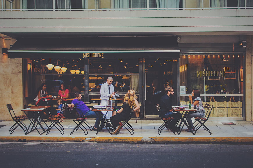 Outdoor dining at Mishiguene restaurant with waiter serving customers
