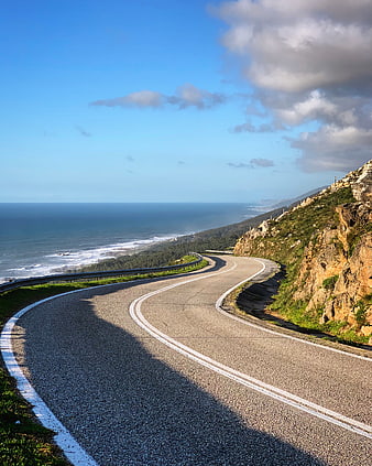 Winding coastal highway road with ocean view and blue sky