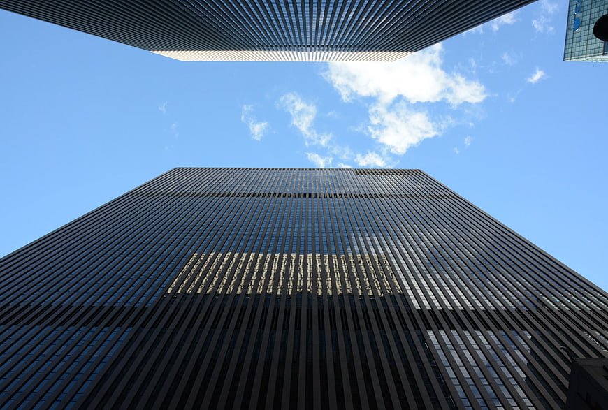 Low-angle view of modern skyscraper against blue sky