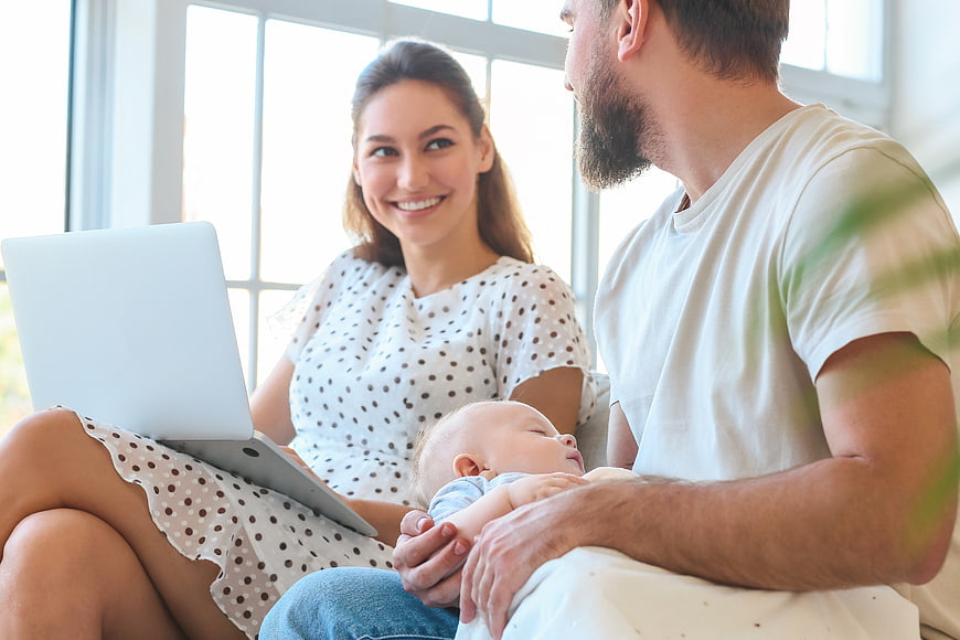 Happy family with sleeping baby and laptop at home