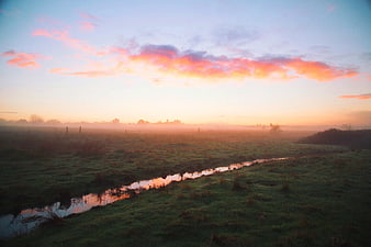 Misty Sunrise Over Green Pasture with Stream