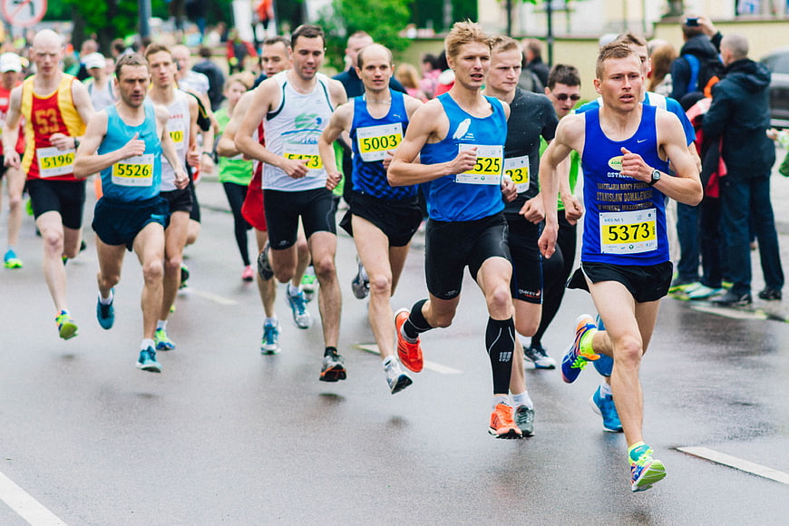 Male Marathon Runners Competing on Wet City Street