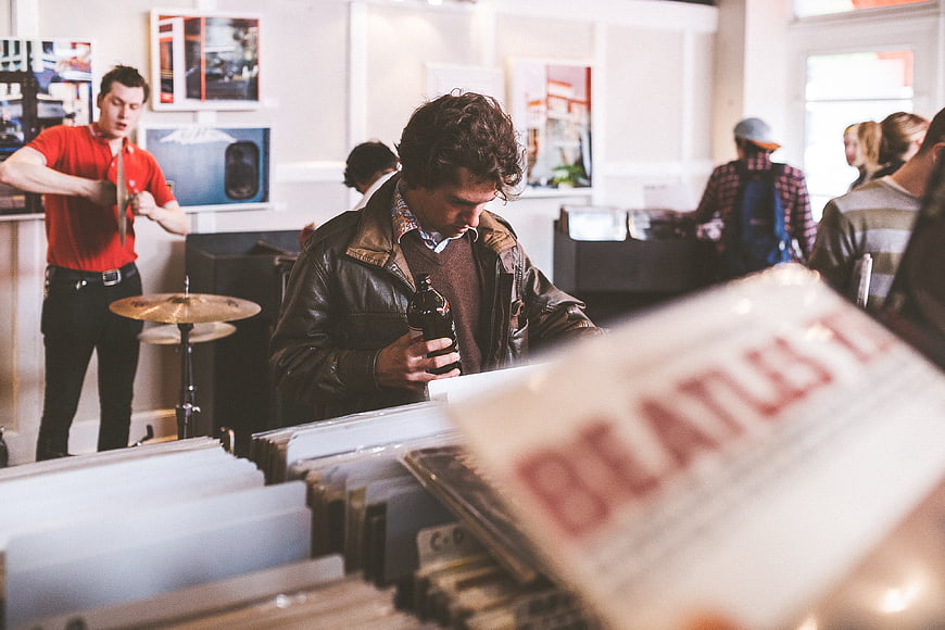 Man browsing vinyl records in a music store with drums