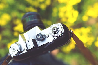 Close-up of vintage film camera with blurred yellow flowers