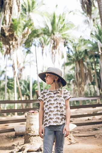 Young Girl in Hat Standing in Tropical Palm Forest