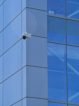 Security Camera on Modern Blue Glass Office Building Facade