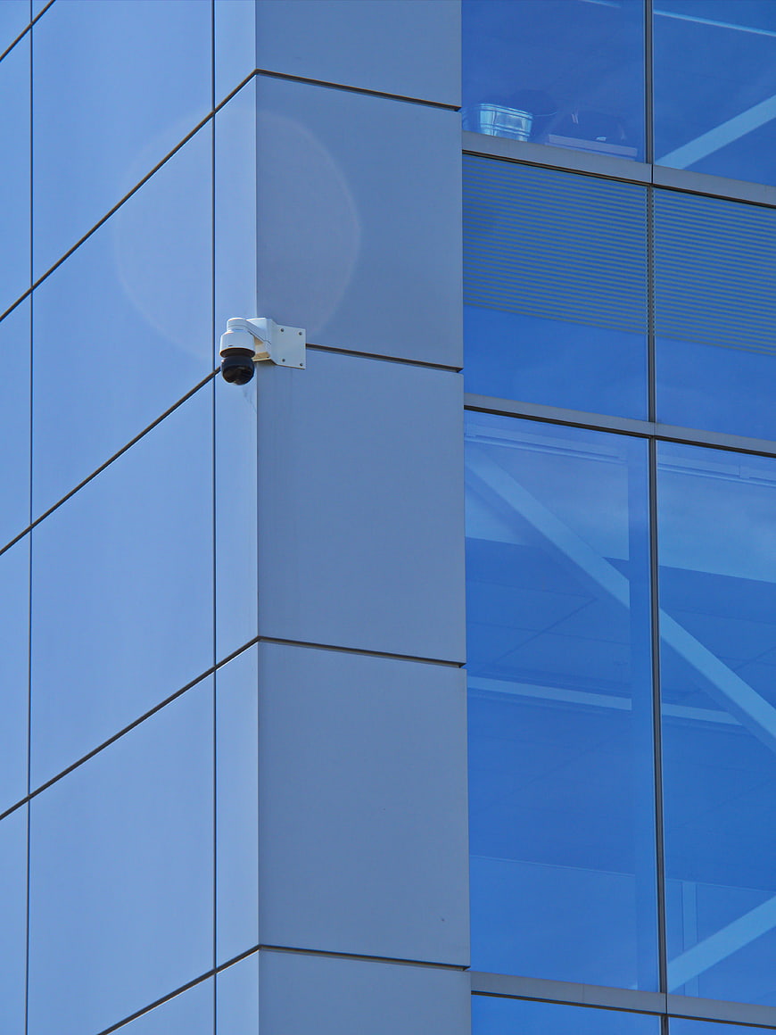 Security Camera on Modern Blue Glass Office Building Facade