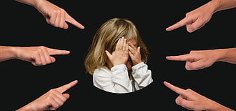 Child Covering Face Surrounded By Pointing Fingers On Black Background