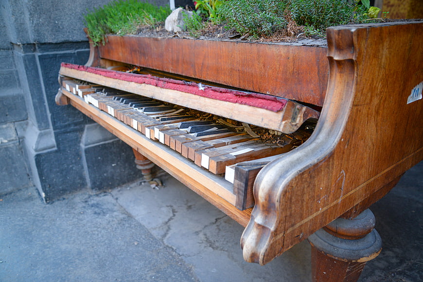 Abandoned vintage upright piano repurposed as outdoor planter