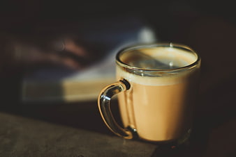 Close-up of a glass mug of latte coffee with blurred background