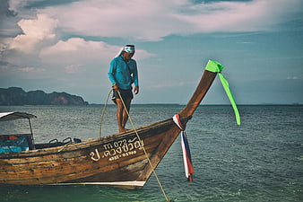Thai Fisherman on Traditional Longtail Boat in Ocean