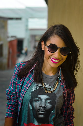 Smiling woman in sunglasses and plaid shirt outdoors