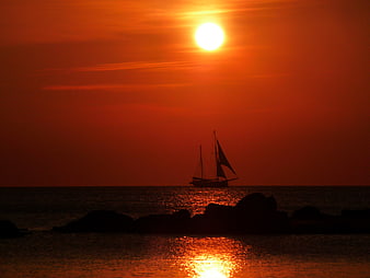 Silhouette of Sailboat on Ocean at Vibrant Red Sunset
