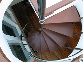 Top-down view of modern brown spiral staircase with metal railing
